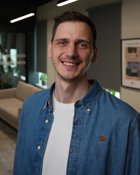Kalvis smiling, wearing a denim shirt